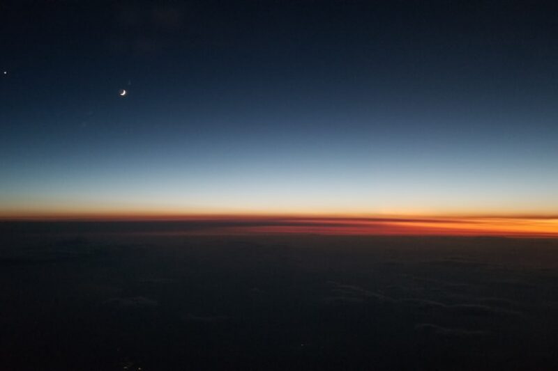 sunset over the horizon seen from a plane window, the day ending in light and dark