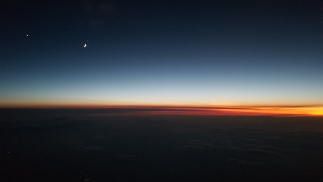 sunset over the horizon seen from a plane window, the day ending in light and dark